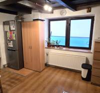A kitchen in a family house with a wood-patterned floor, a table, and a refrigerator.