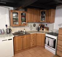 A kitchen in a family house with wooden cabinets, appliances, and a white wall.