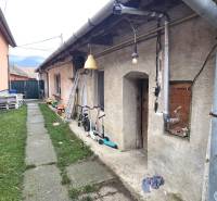Exterior of a family house in Dolné Orešany with a walkway, children's toys, and greenery.