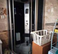 Bathroom in a family house with a massage shower cabin and a laundry basket.