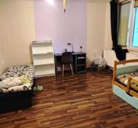 Interior of a family house with beds and wood-patterned flooring.