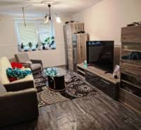Living room in a family house with sofas and a TV, floor with wooden decor.