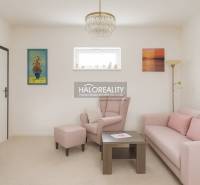 Living room with a pastel sofa and armchair in a family house, decorative paintings on the walls.