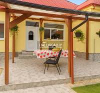 Terrace at a family house in Beša with flowers on a yellow facade and a wooden pergola.
