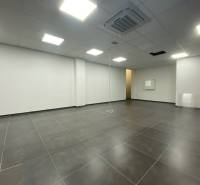 Commercial space with dark flooring and white walls, illuminated by ceiling lights.