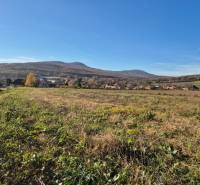 View of the plots - housing in Velčice with hilly landscape in the background.