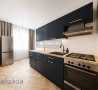 A kitchen in a 3-room apartment with dark furniture and a wooden decor floor.