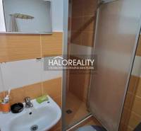 Bathroom with a sink and shower in a studio apartment, orange and white tiles.