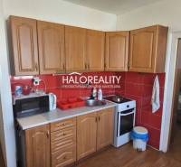 A kitchen in a studio apartment with wooden cabinets, a microwave, and a stove.