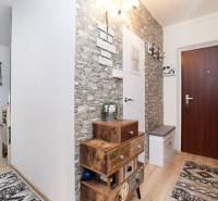 A hallway in a 2-room apartment with decorative stone walls and a floor with a wood decor.