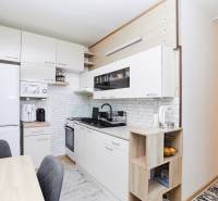 A kitchen in a 2-room apartment with white cabinets and a wooden decor floor.