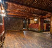 Interior with wood-patterned flooring, brick and stone walls, ceiling with wooden beams.