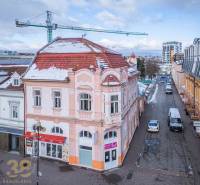 A building in the city of Poprad with historical architecture and a snow-covered roof.
