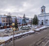 Square with a church and a Christmas tree in Poprad, snow-covered buildings, urban architecture.