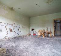 An abandoned room with graffiti on the walls, chairs piled on the table. The building needs renovation.