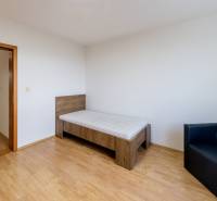 A room with a bed and a chair, a floor with a wooden decor in a three-room apartment.