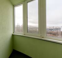 A glazed balcony in a 3-room apartment with a view of buildings and nature.
