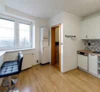 A kitchen in a 3-room apartment with a wooden decor floor and white cabinets.
