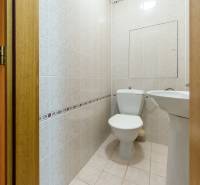 Bathroom in a 3-room apartment with a toilet and a sink, light tiles.