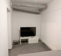 A room in a family house with a television on a white table and a gray carpet.