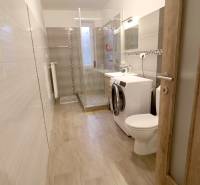 A bathroom in a family house with tiled walls and a wooden decor floor.