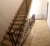 A staircase with a metal railing and a wooden decor floor in a family house.