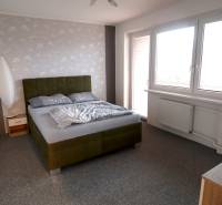A bedroom in a family house with an upholstered bed and a gray carpet.