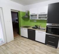 A kitchen in a family house with a wooden decor floor and green tiles.