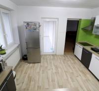 A kitchen in a family house with a wooden decor floor and green tiles.