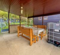 Covered terrace with a table, benches, and a view of the gardens in Bytča.