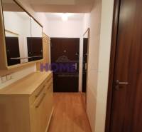 The entrance hall in a 2-room apartment with a wooden decor floor, mirrors, and wardrobes.