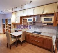 A kitchen unit with a wooden decor and a dining table in a 2-room apartment.