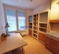 A study in a 2-room apartment with a wooden decor floor, a desk, and a bookshelf.