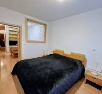 A bedroom with a wide bed, nightstands, and a wooden decor floor in a 2-room apartment.