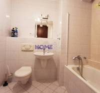 A bathroom in a 2-room apartment with a bathtub, sink, and toilet, tiled with white tiles.