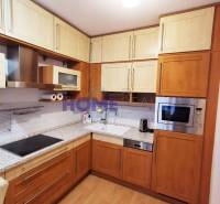 A kitchen in a 2-room apartment with corner-arranged cabinets and a wooden decor floor.