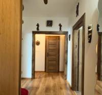 A hallway in a 3-room apartment with a wooden decor floor and wooden doors.