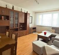 Living room in a three-room apartment with a wooden decor floor and a large sofa set.