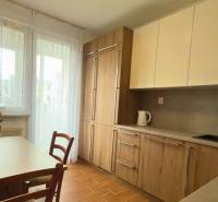 A kitchen in a 3-room apartment with wooden decor and light furniture, elegant flowers on the table.
