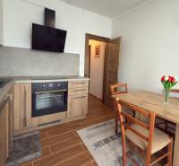 A kitchen in a 3-room apartment with a wooden decor, a dining table, and a kitchen unit.