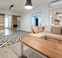 A living room in a three-room apartment with a wooden decor floor and comfortable seating.