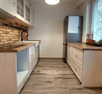 A kitchen in a 3-room apartment with a wooden decor floor and brick cladding.