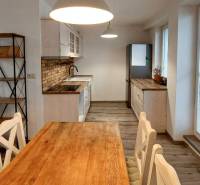 A kitchen in a 3-room apartment with a rustic table and bright lighting, flooring with a wooden decor.
