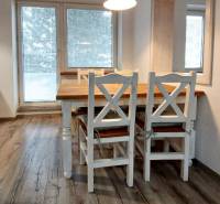 Dining area with wood-patterned flooring in a 3-room apartment with white furniture.