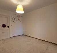 A room in a 3-room apartment with a carpet, a bright lamp, and wall decorations.