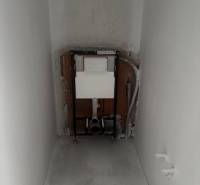 Installation for a wall-hung toilet in the bathroom of a family house. The walls and floor are unfinished.