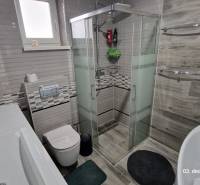 Bathroom in a family house with a toilet, shower, and bathtub, floor with wooden decor.