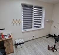 A room in a family house with a wooden decor floor, a weight bench, and a table.