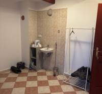 Interior of an office with a sink, coat rack, and tiled floor.