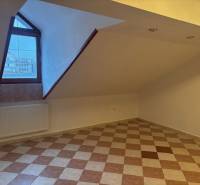 Attic office with tiles and a window, heated by a radiator.